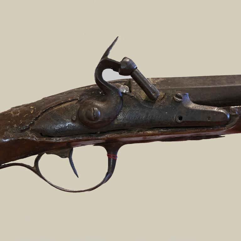 L’image est un détail du fusil à silex offert par le Roi Louis XV au chasseur d’esclaves fugitifs, François Mussard. L’arme a été modifiée et ne fait pas appel à une platine à silex mais à un système à capsule dit à percussion. 
